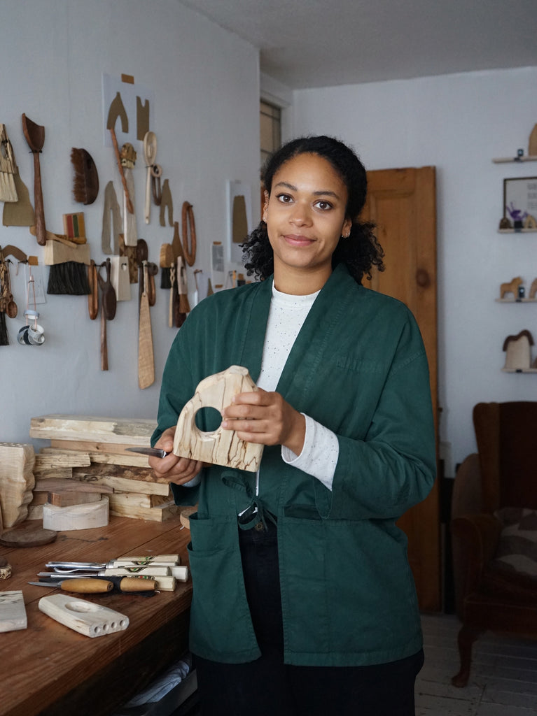Grain and Knot Sophie looking to camera in studio holding wooden vase